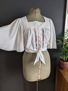 Gorgeous 70's Woodstock/California vibes vintage top with Angel wings. Button and tie round waist.  Good condition apart from a bit of fabric snagging. Shown in photos. 100% Triacetate Would look gorgeous with a pair of highwaisted jeans. Size UK 10/12/14 Depending on fit - Mannequin is a size 8 Chest 34-38 inches  The bust is actually open so hard to measure but going on the waist I'd say it would fit between a size 34 and 38 inch bust.  Waist 35 inches (untied, can be made smaller) Length 18 i Highwaisted Jeans, California Vibe, Seventies Fashion, Cropped Blouse, Angel Sleeve, Crop Blouse, Woodstock, Bat Wings, Vintage Tops