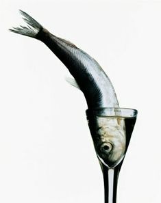 a fish in a wine glass with water inside it and its tail sticking out from the bottom