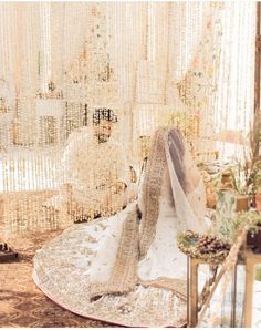 a wedding dress and veil sitting on a table in front of beaded curtaines