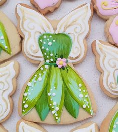 decorated cookies in the shape of flowers and fairy wings on a white table with pink and green decorations