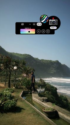 a man standing on top of a lush green hillside next to the ocean