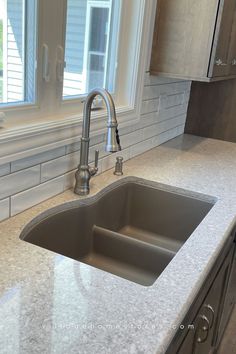 a kitchen sink sitting under a window next to a counter