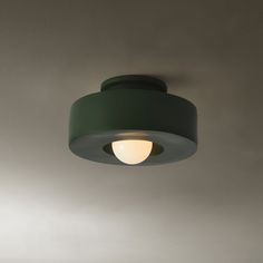 a green light fixture hanging from the ceiling in a room with white walls and flooring