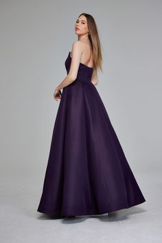 a woman in a long purple dress looking off to the side with her hand on her hip