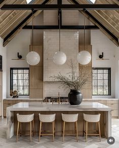 a large kitchen with an island in the middle and four stools at the end