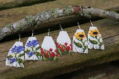 seed bead earrings with flowers on them hanging from a tree branch in the woods