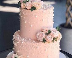 a three tiered cake with pink flowers on top and pearls all around the edges