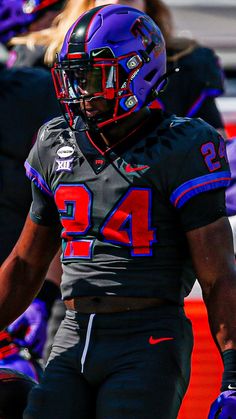 a football player wearing a helmet and holding his hand out to the sidelines with other players in the background