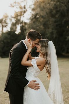 a bride and groom standing together in a field