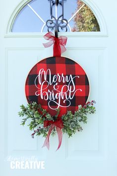 a red and black plaid christmas wreath hanging on a white door with the words merry bridge above it