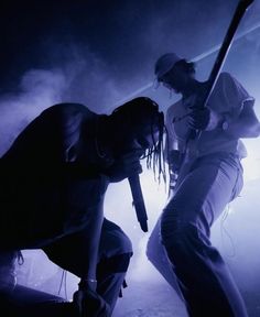 two people on stage with one holding a baseball bat and the other looking down at something