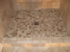 a walk in shower sitting next to a tiled wall and floor with tile on it