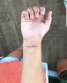 a woman's arm with a small wave tattoo on her left wrist and the word love written across it