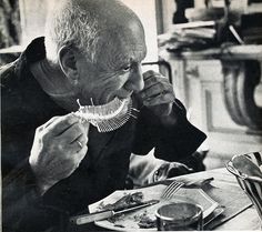 an old man eating food at a table in front of his face and looking off to the side