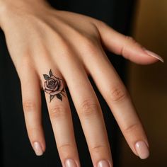 a woman's hand with a rose tattoo on the middle finger and an open ring