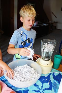 a young boy is making shredded paper in a blender