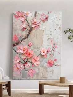 a large painting with pink flowers on it in a white living room next to a coffee table