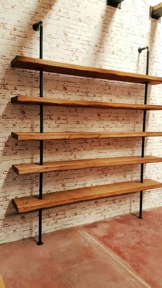 the shelves are made from wood and have black metal brackets on them, along with brick walls