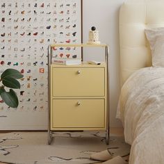 a yellow dresser next to a bed in a room with pictures on the wall behind it