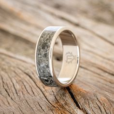 a wedding ring with antler wood inlays the center on a wooden surface