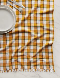 an orange and white checkered table cloth with a plate, fork and knife on it