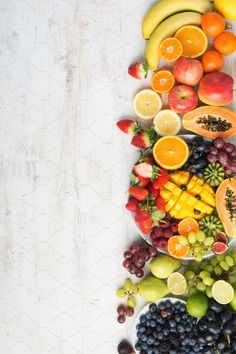 an arrangement of fruits arranged in the shape of a line on a white table top