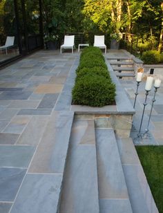 an outdoor patio with stone steps and plants in the center, surrounded by lawn furniture