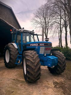 a blue tractor parked in front of a barn