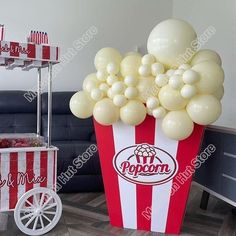 a popcorn box filled with white balloons sitting on top of a floor next to a couch