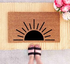 a person standing in front of a door mat with the sun coming out on it