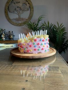 a birthday cake with sprinkles and candles sitting on a wooden platter