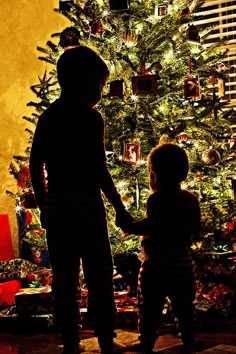 two children standing in front of a christmas tree