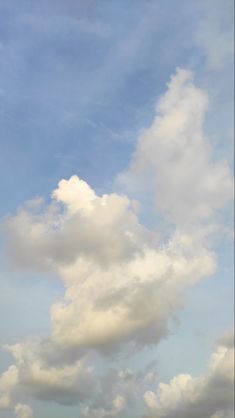 a plane flying in the sky with some clouds above it and another airplane on the ground