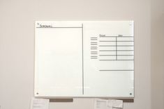 a white board mounted to the side of a wall next to papers on top of it