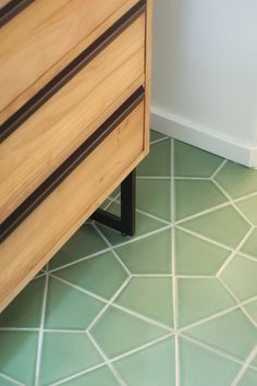 a wooden dresser sitting on top of a green floor next to a white and brown wall