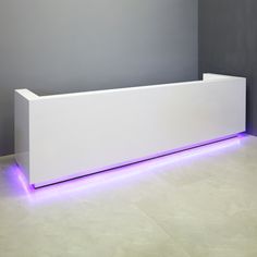 a white reception table with purple lights on the side and a grey wall behind it