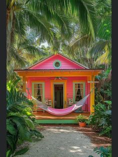 a pink and yellow house with hammock hanging from it's front porch