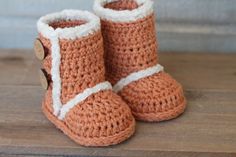 a pair of crocheted baby boots sitting on top of a wooden floor next to a wall