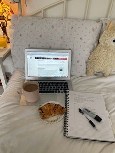 an open laptop computer sitting on top of a bed next to a cup of coffee