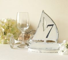 a sailboat is sitting next to a wine glass and some flowers on a table