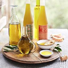 three bottles of olive oil on a wooden tray