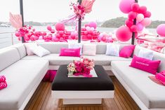 a white couch sitting on top of a wooden floor covered in pink and white pillows