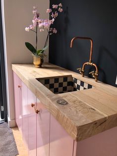 a kitchen with pink cabinets and a checkerboard counter top in the center, next to a gold faucet