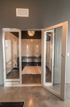 an empty room with glass doors leading to a bed in the corner and a shower stall