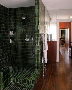 a bathroom with green tiles and wooden floors