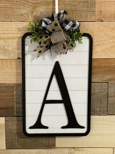 a door hanger with the letter a on it and a bow hanging from it