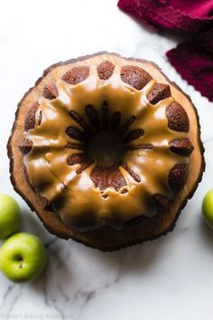 a cake with icing sitting on top of a table next to some green apples