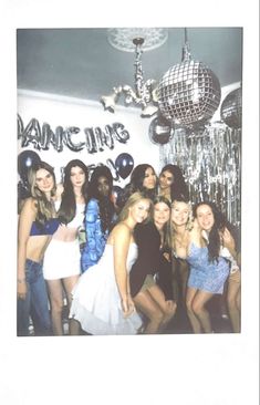 a group of women standing next to each other in front of a disco ball hanging from the ceiling