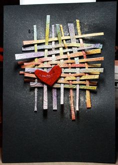 a piece of art made out of strips of paper with a red heart on it