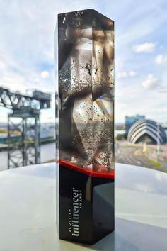 a glass block sitting on top of a table next to a river and bridge in the background